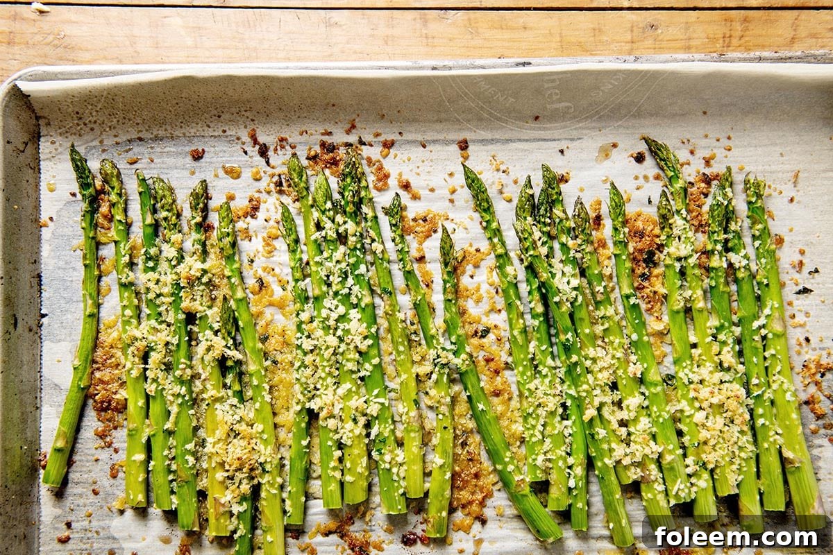 Roasted asparagus with garlic and Parmesan on baking pan.