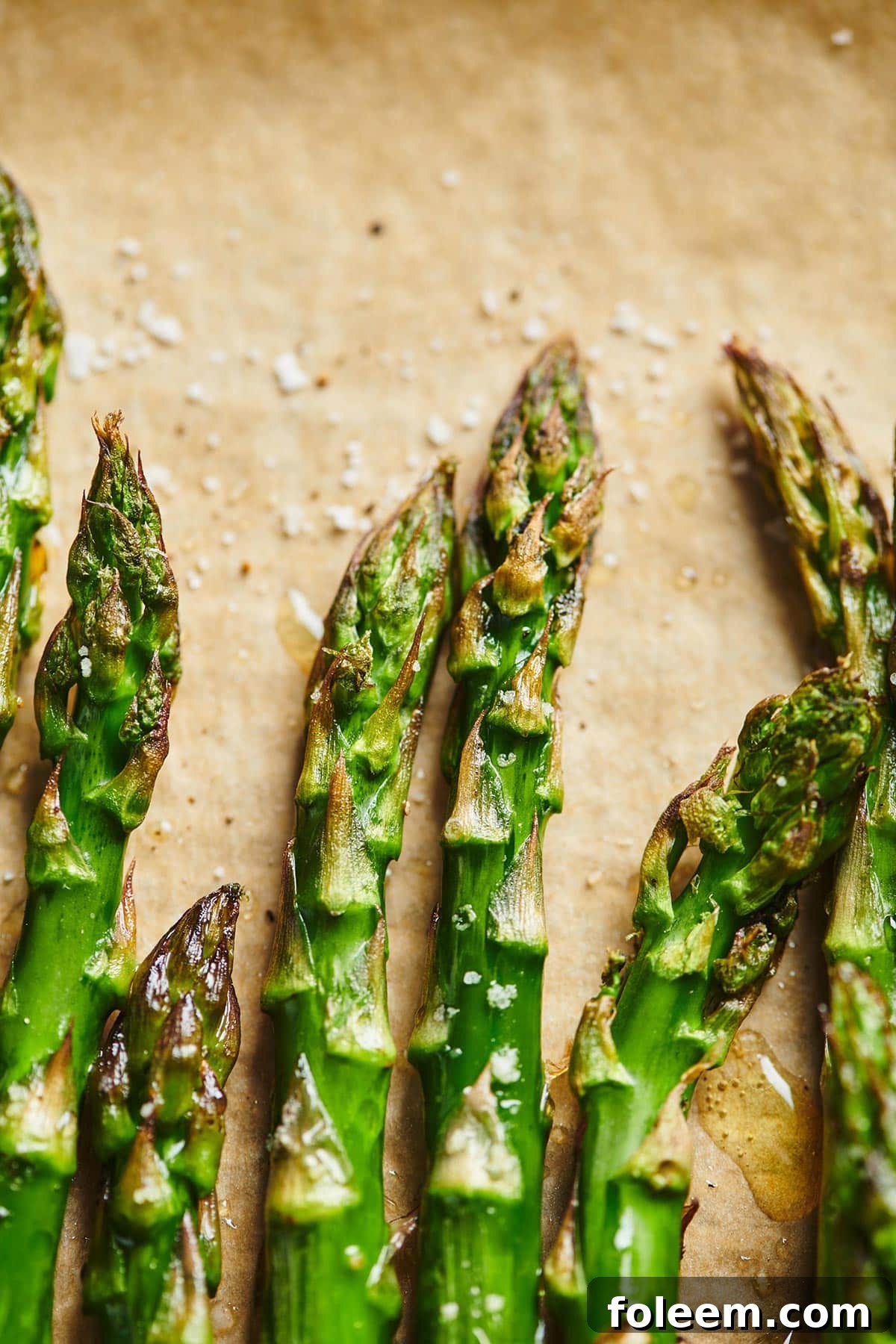 Roasted Asparagus with salt and pepper on parchment paper.