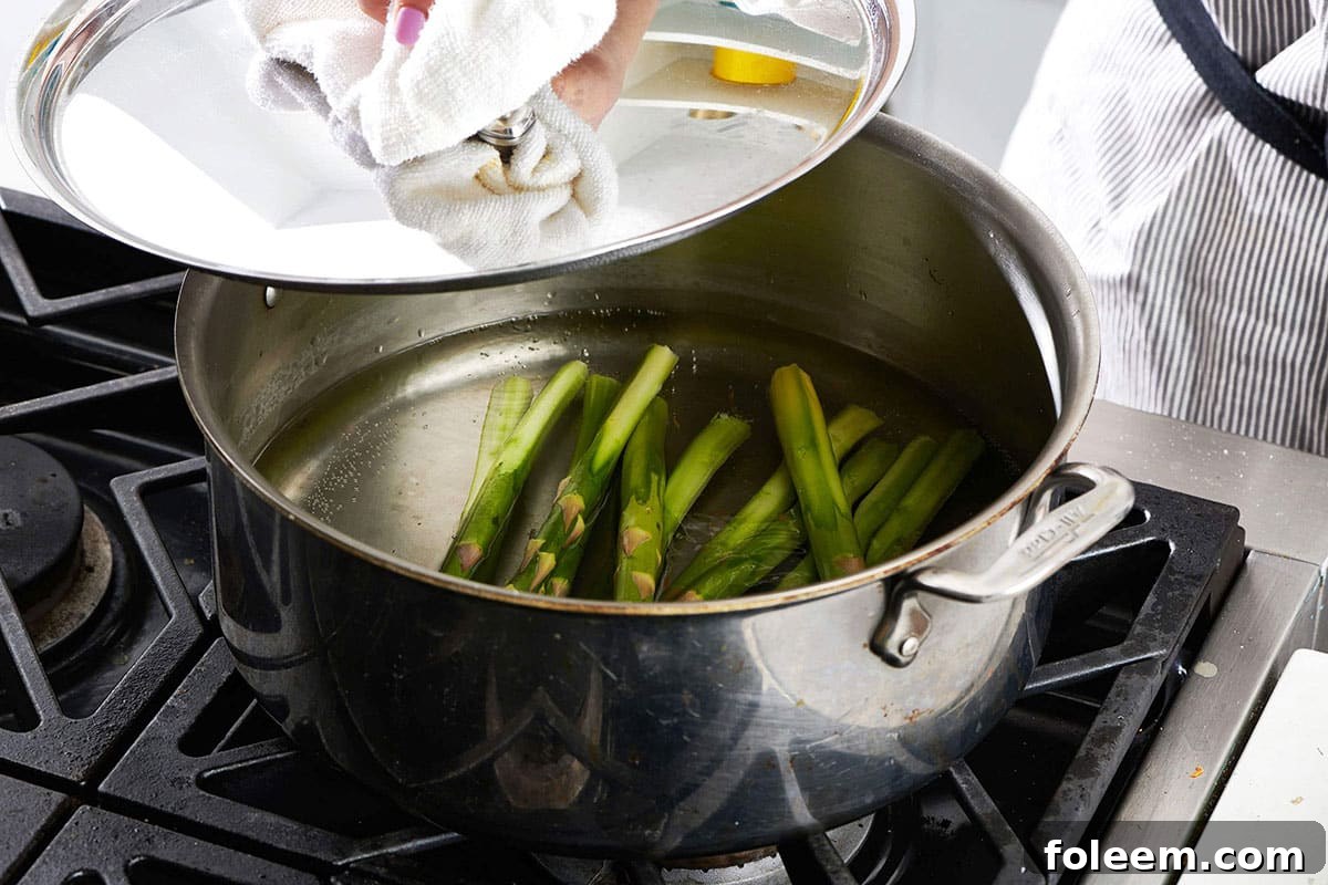 Blanching asparagus in pot of water on stove.