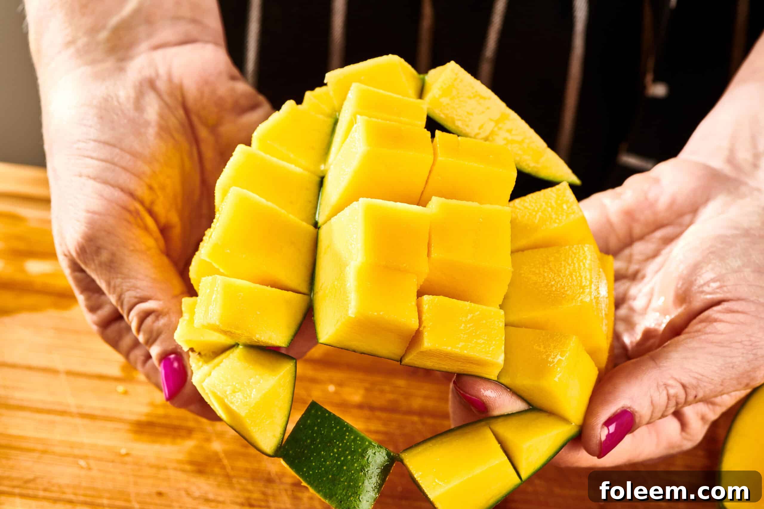 Woman holding scored mango to show cubes.