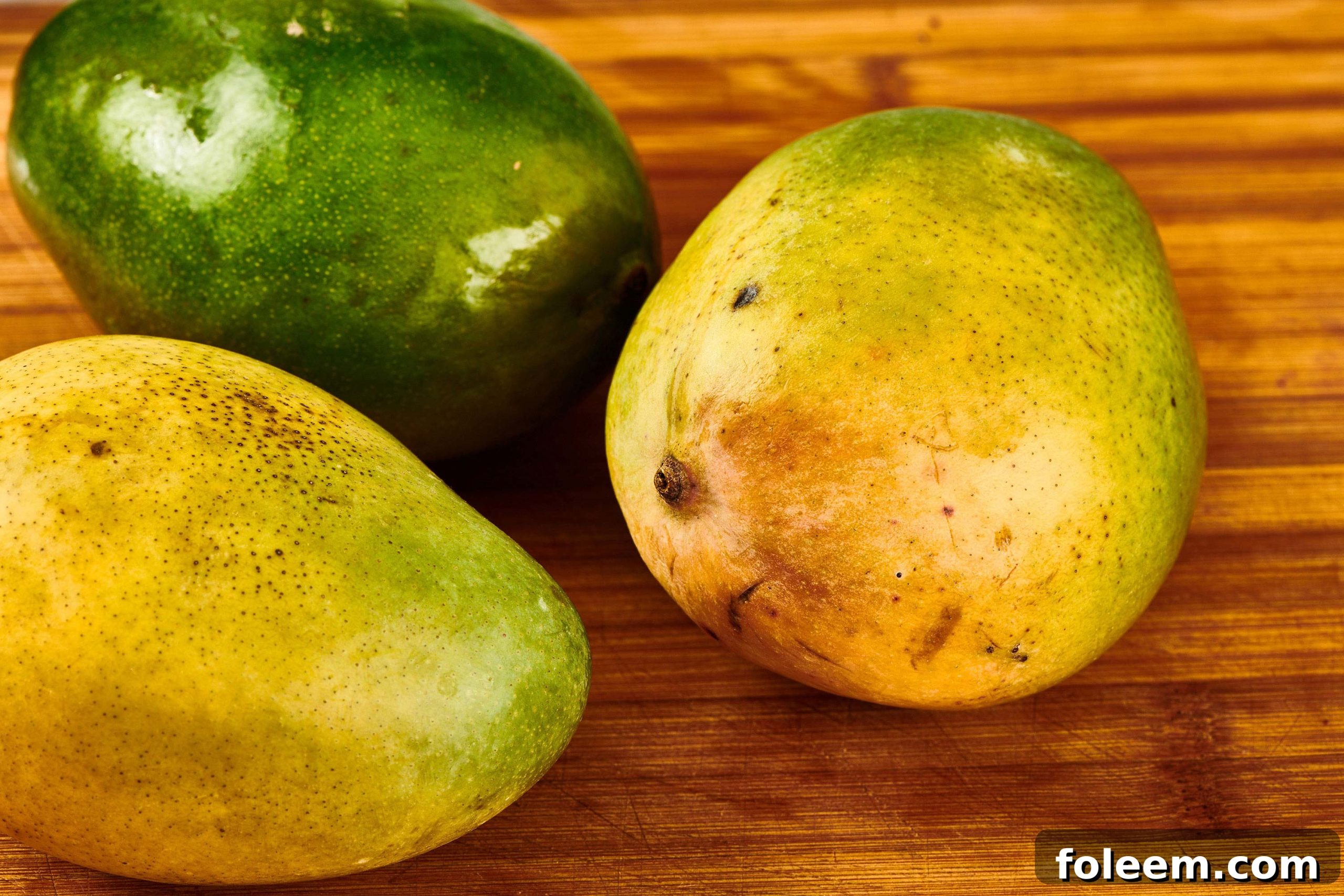 Mangos on a wooden cutting board.