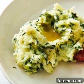 Mound of Colcannon topped with melted butter on a white plate.