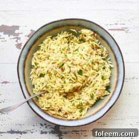 Orzo pasta salad with red onion and mint in serving bowl.