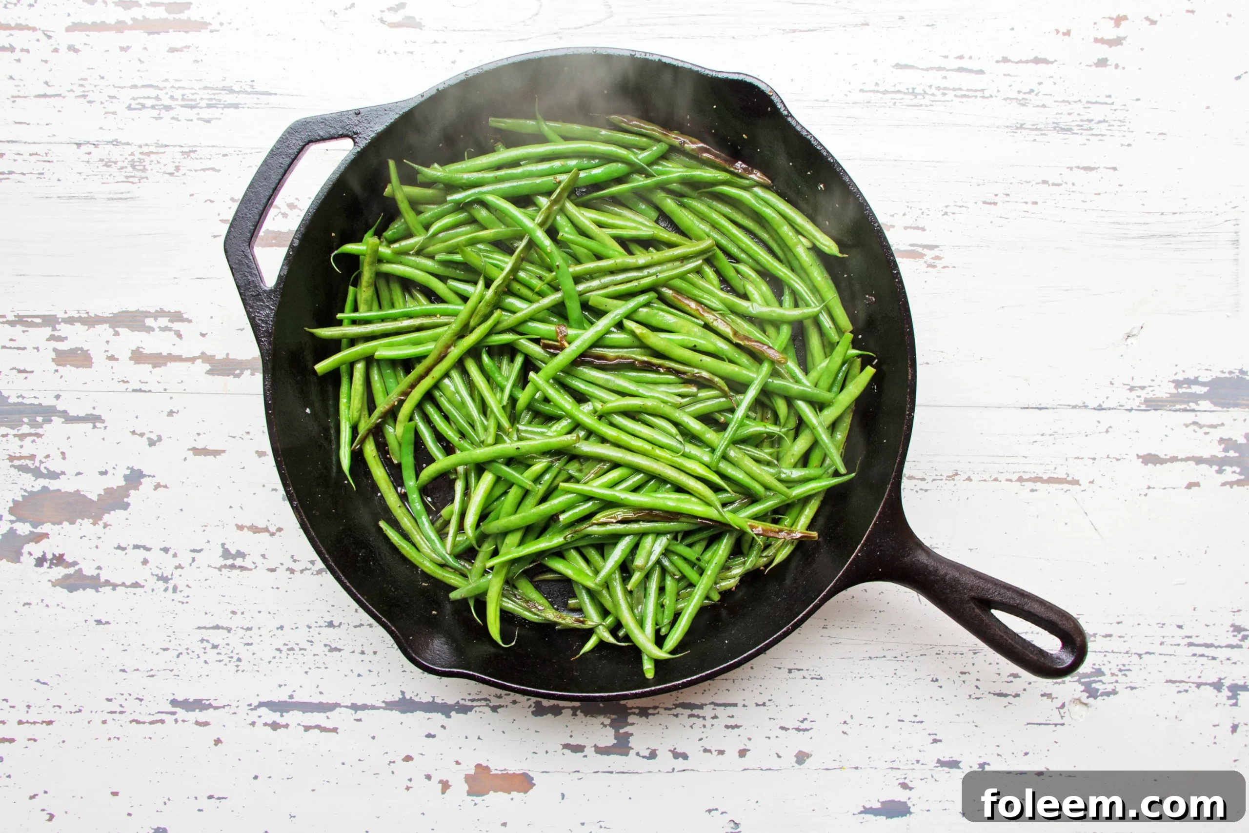 Sautéed Haricot Verts in steaming hot cast iron pan.