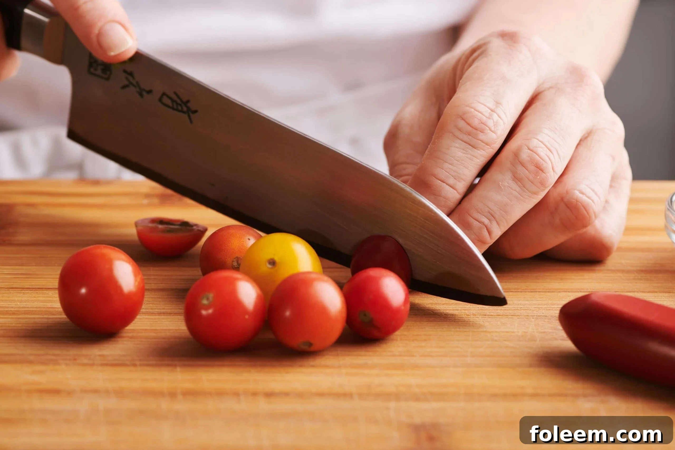 Woman chopping cherry tomatoes on cutting board.