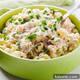Spoon in a green bowl filled with potato salad.