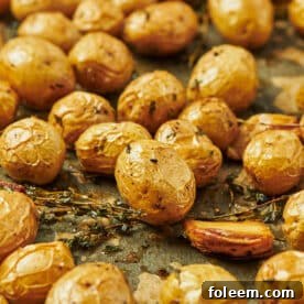 Duck fat roasted potatoes with garlic and thyme on baking sheet.
