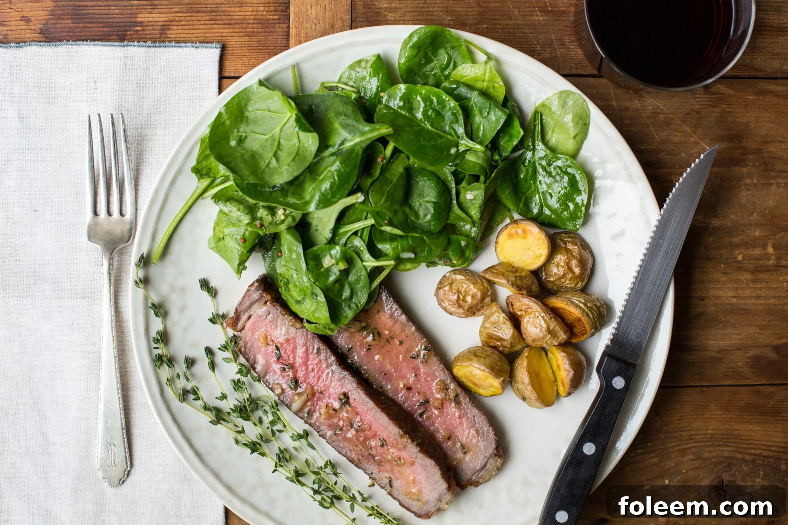 Rib Eye Steaks with Thyme-Garlic Butter on white plate.