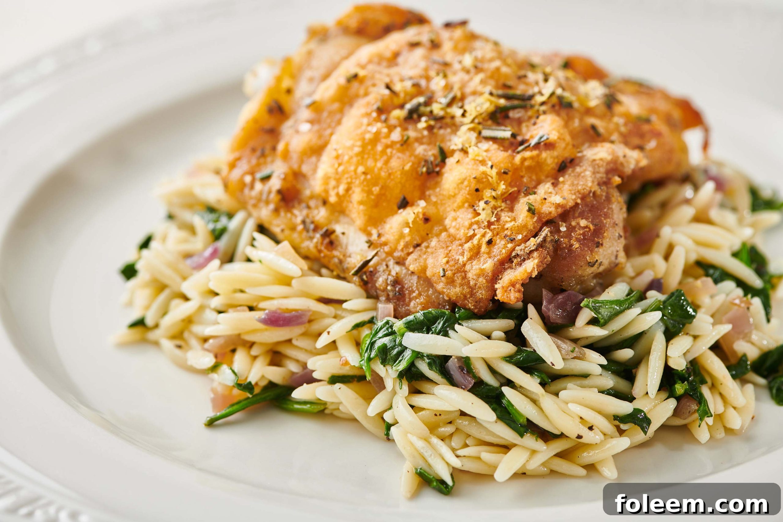Lemon Rosemary Chicken and rice pilaf on white plate.