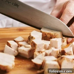 Slicing chicken into cubes.