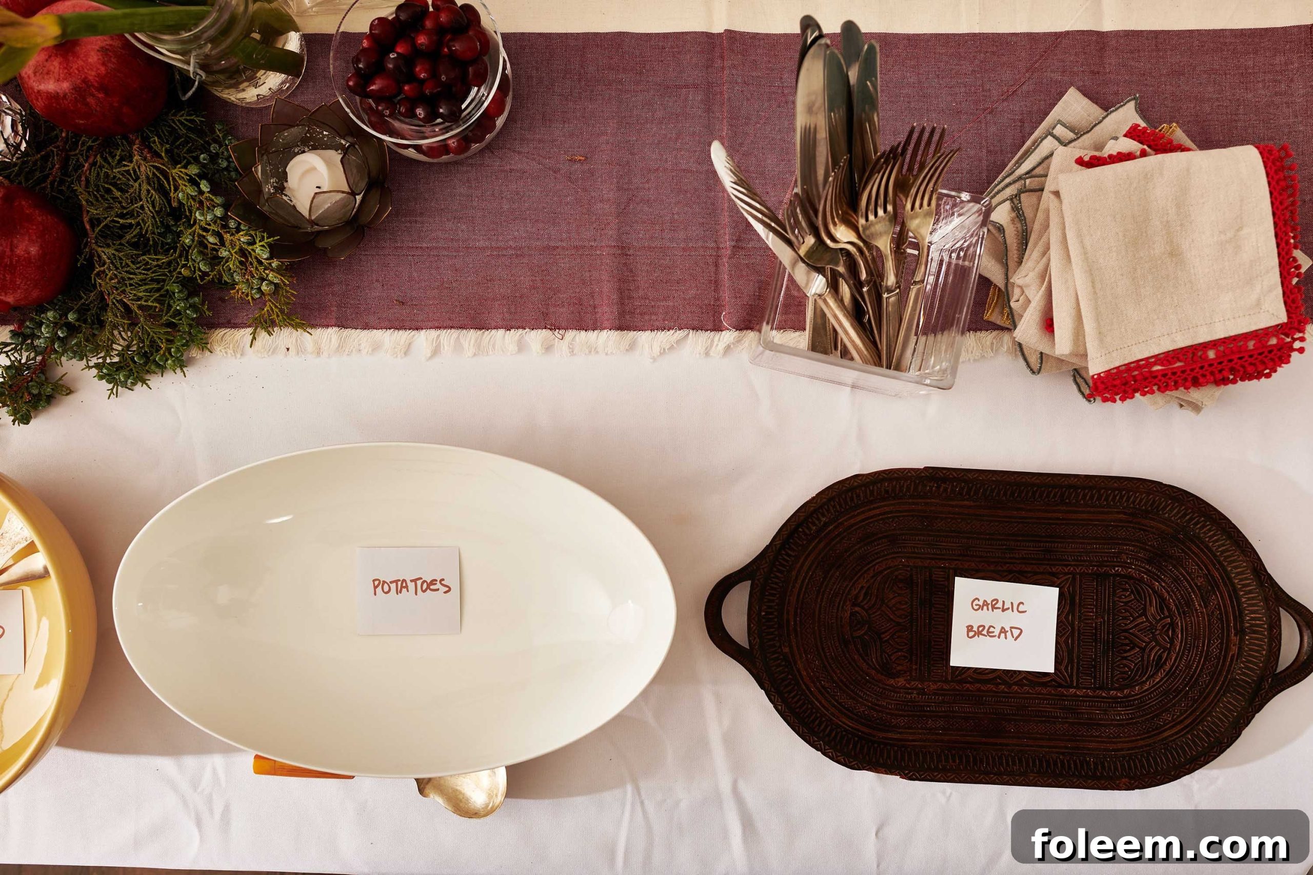 Decorated table with serving dishes labelled "Potatoes" and "Garlic Bread."
