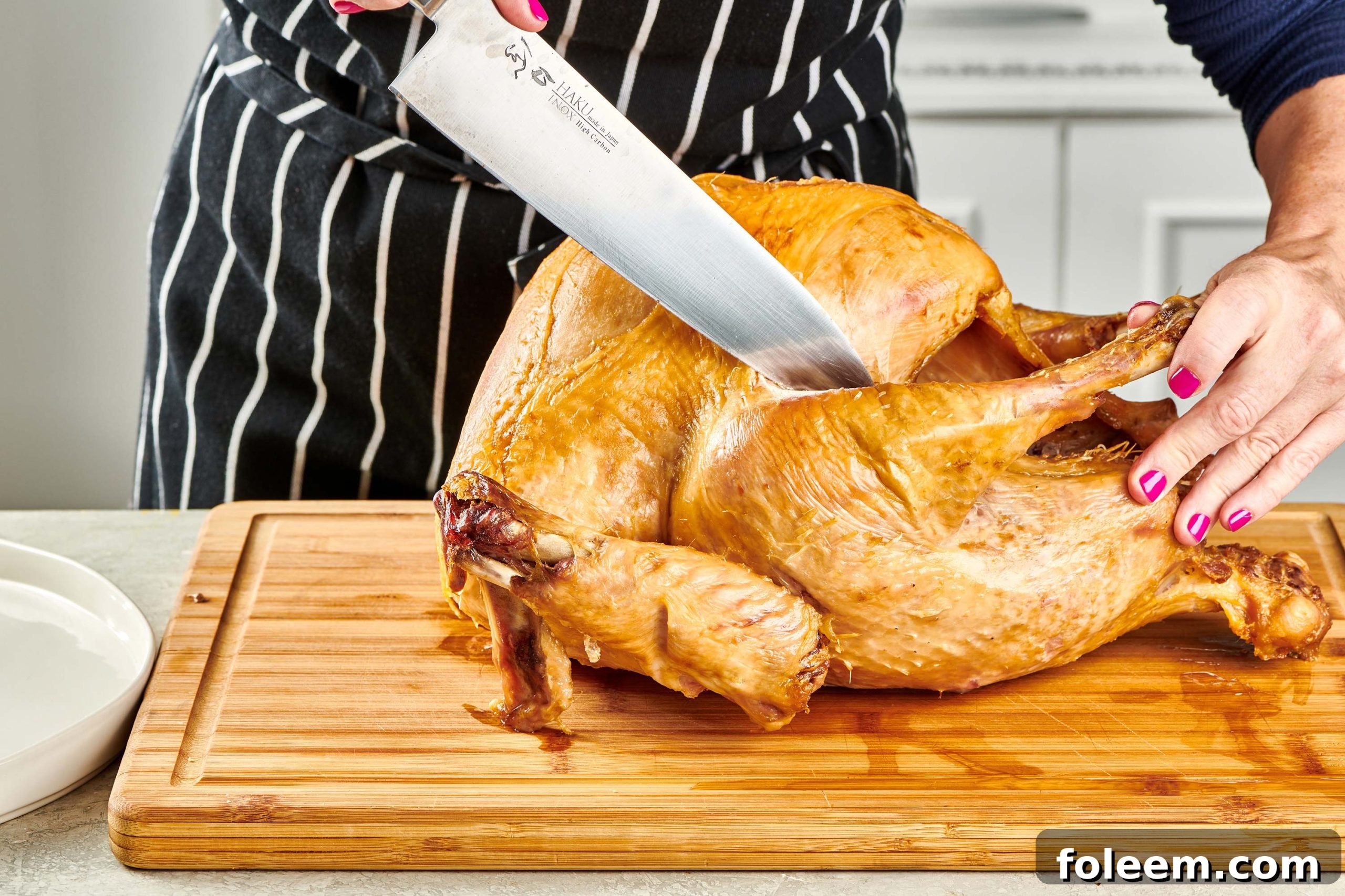Woman removing turkey legs from a roast turkey.
