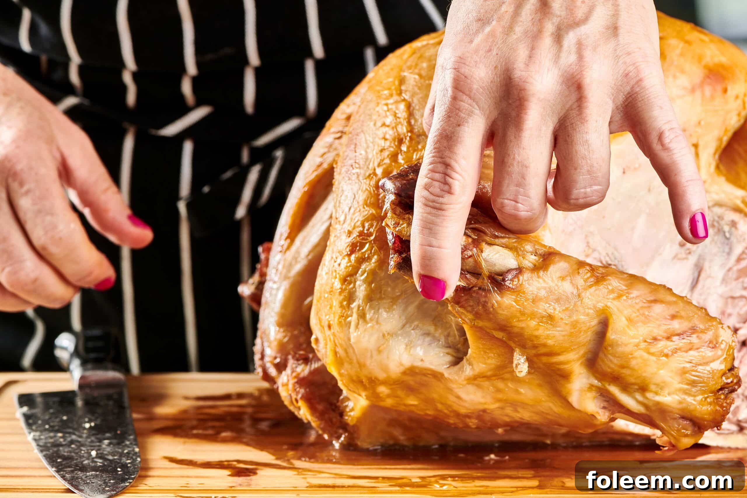 Woman removing turkey wings from a roast turkey.
