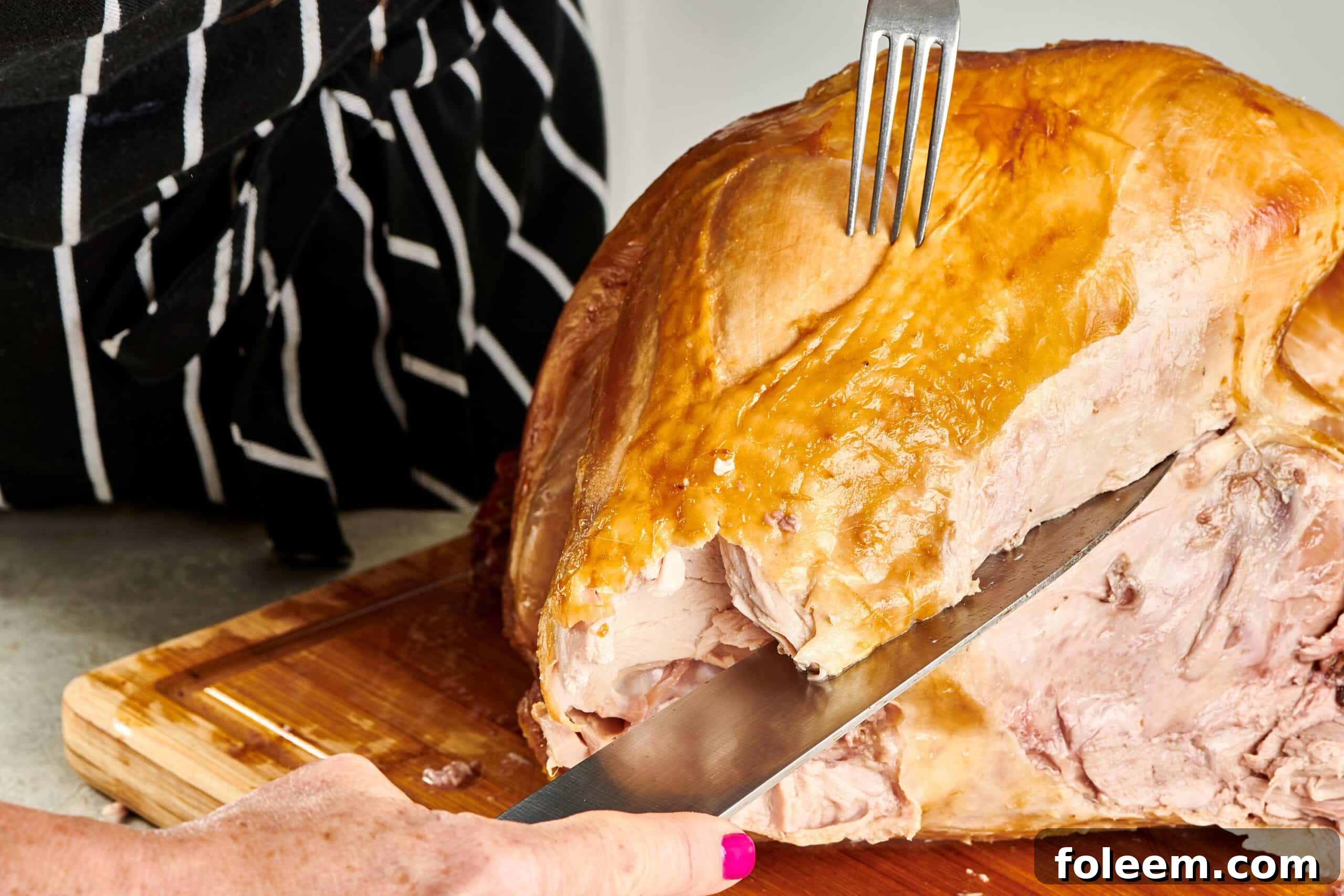 Woman removing turkey breast from a roast turkey.
