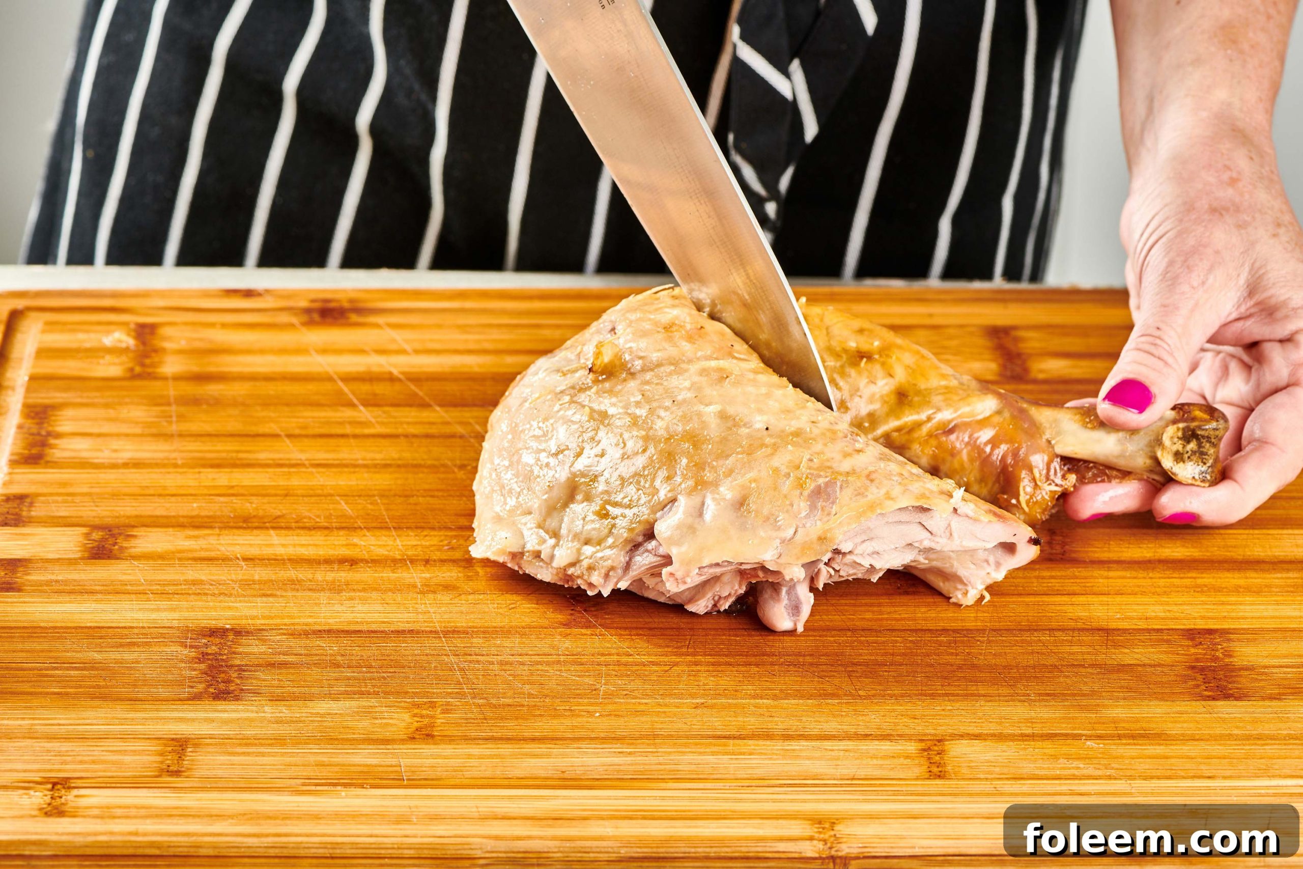 Woman separating turkey thigh and drumstick with a knife