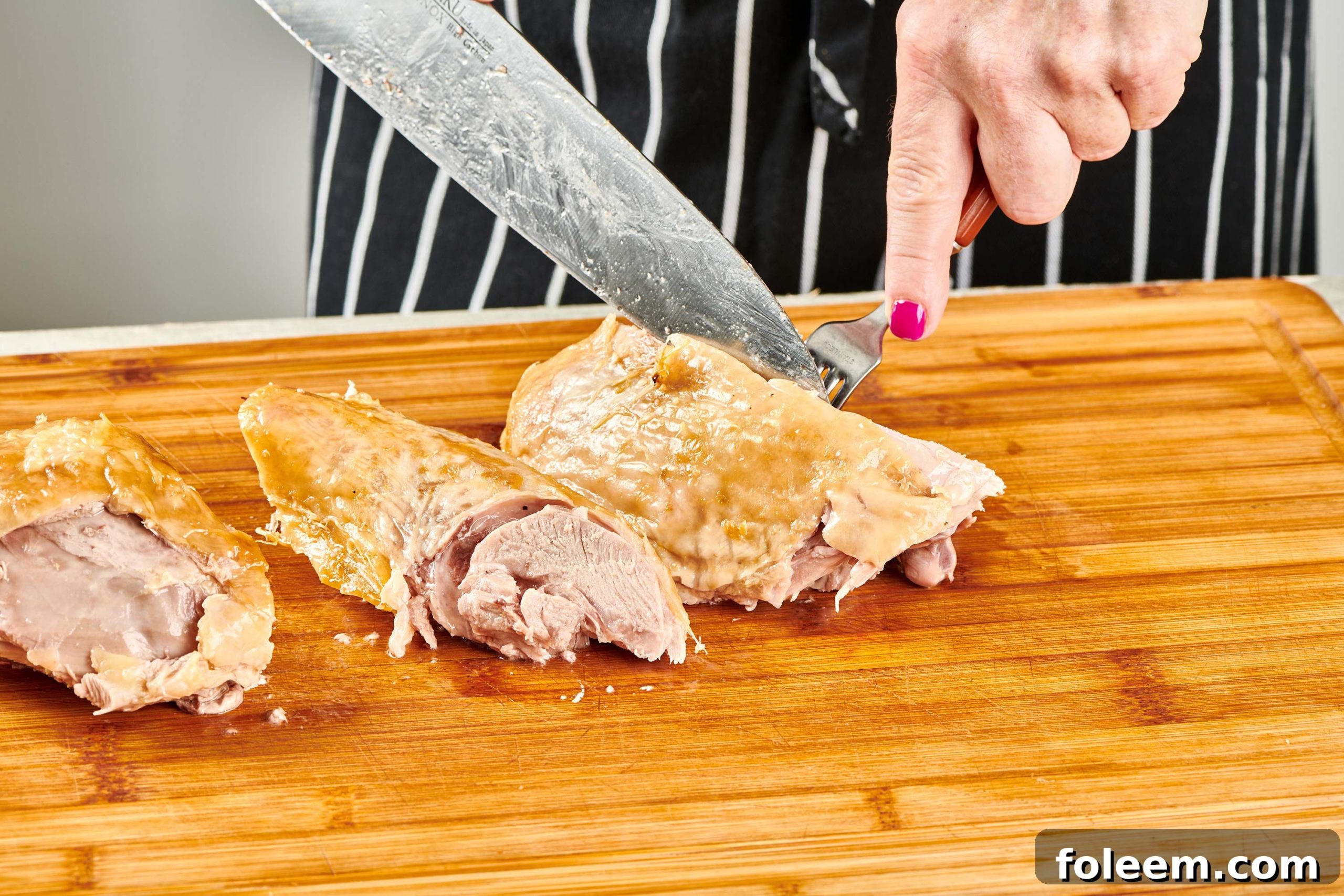 Woman carving turkey thigh.