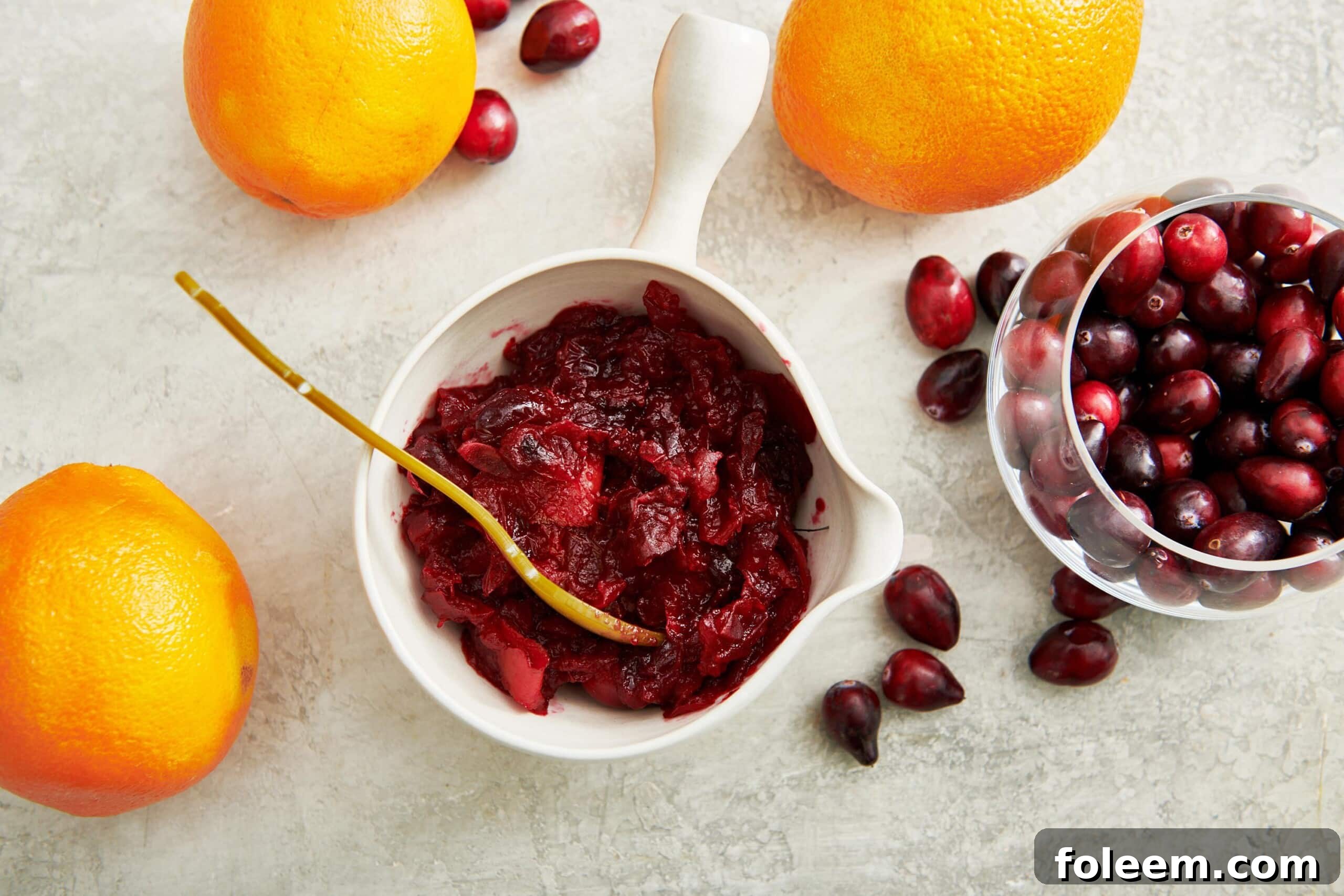 Cranberry Orange Sauce in bowls on table with oranges