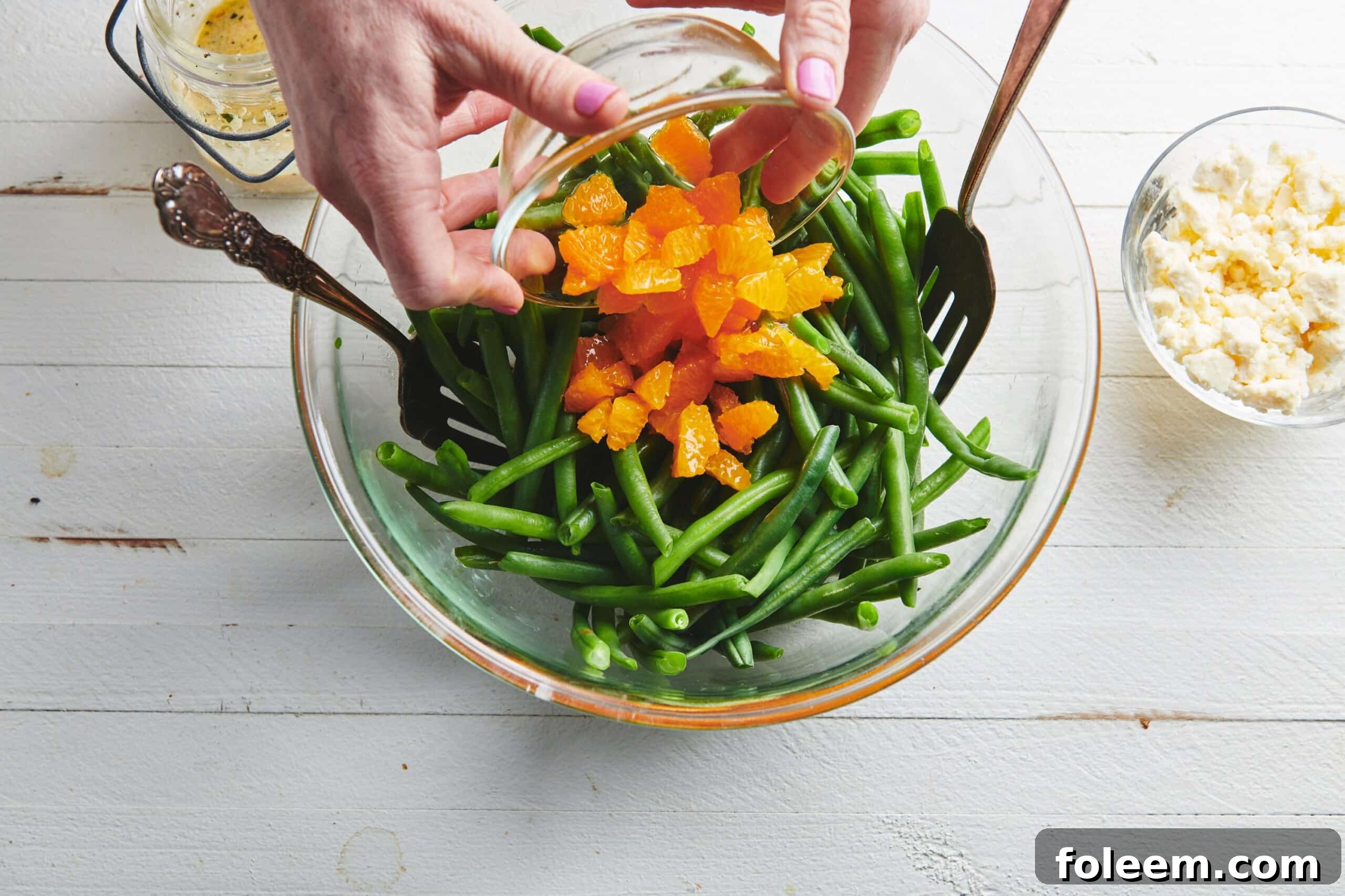 Woman pouring Clementine Oranges into a bowl of green beans.