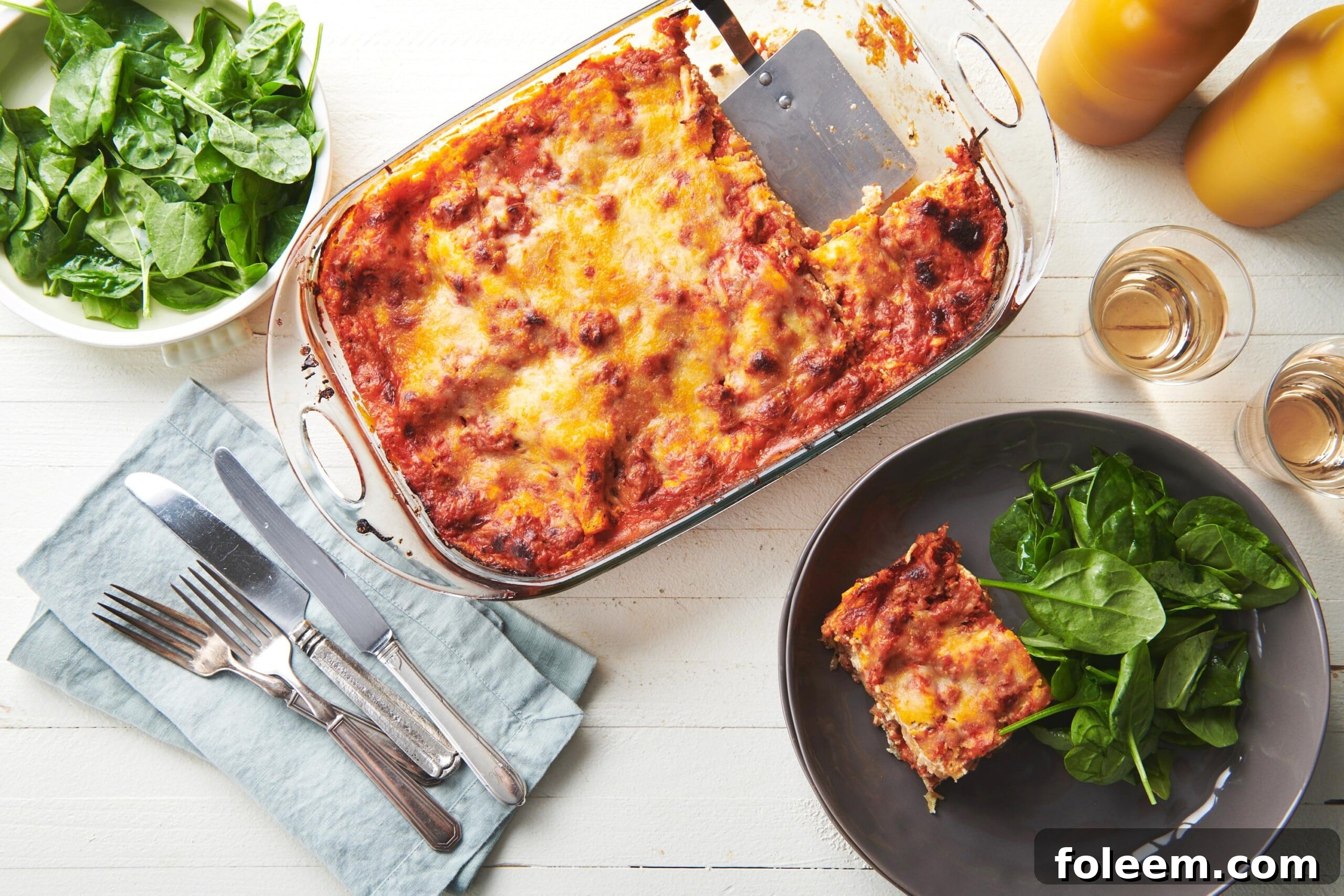 Turkey lasagna in pan on table with plates and salads.