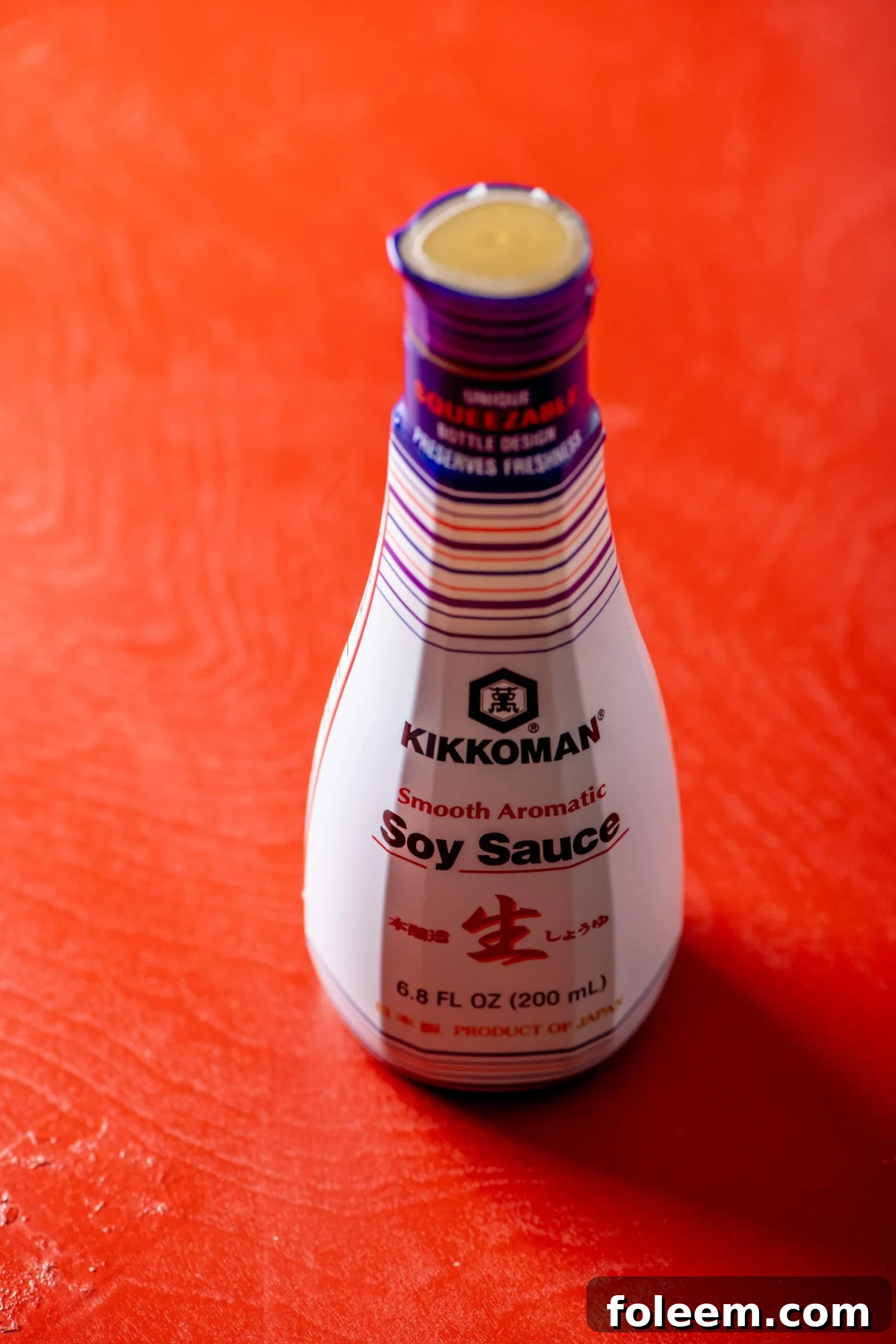 Jar of Kikkoman Soy Sauce on red table.