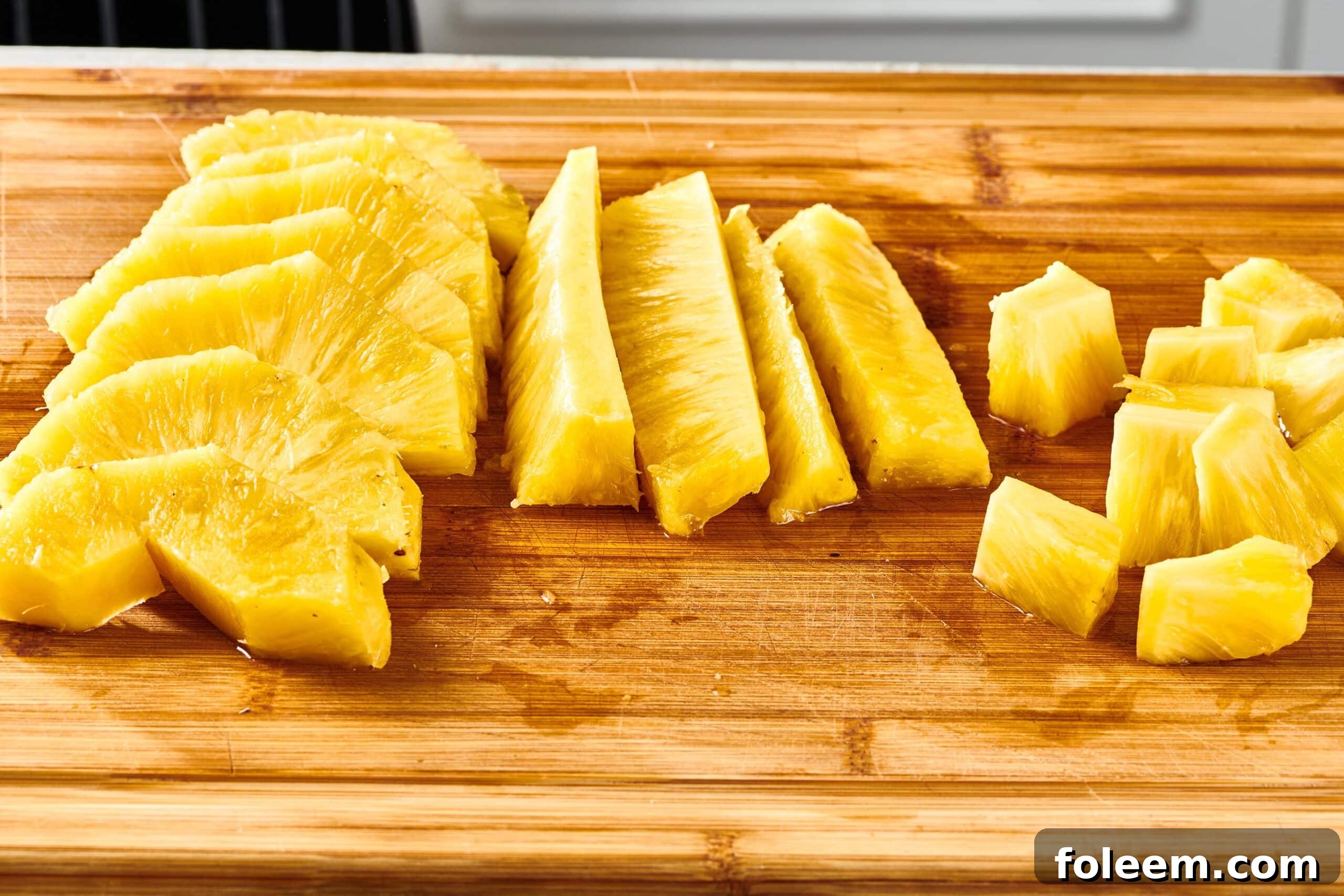 Various sized pieces of pineapple on a cutting board.