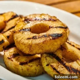 Grilled pineapple slices on white plate at picnic.