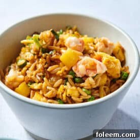Fried rice with pineapple and shrimp in white bowl on table.