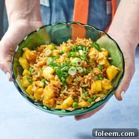 Woman holding green bowl with pineapple fried rice.