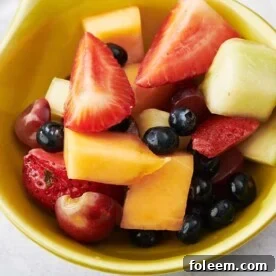 Mixed fruit salad in small yellow bowl.