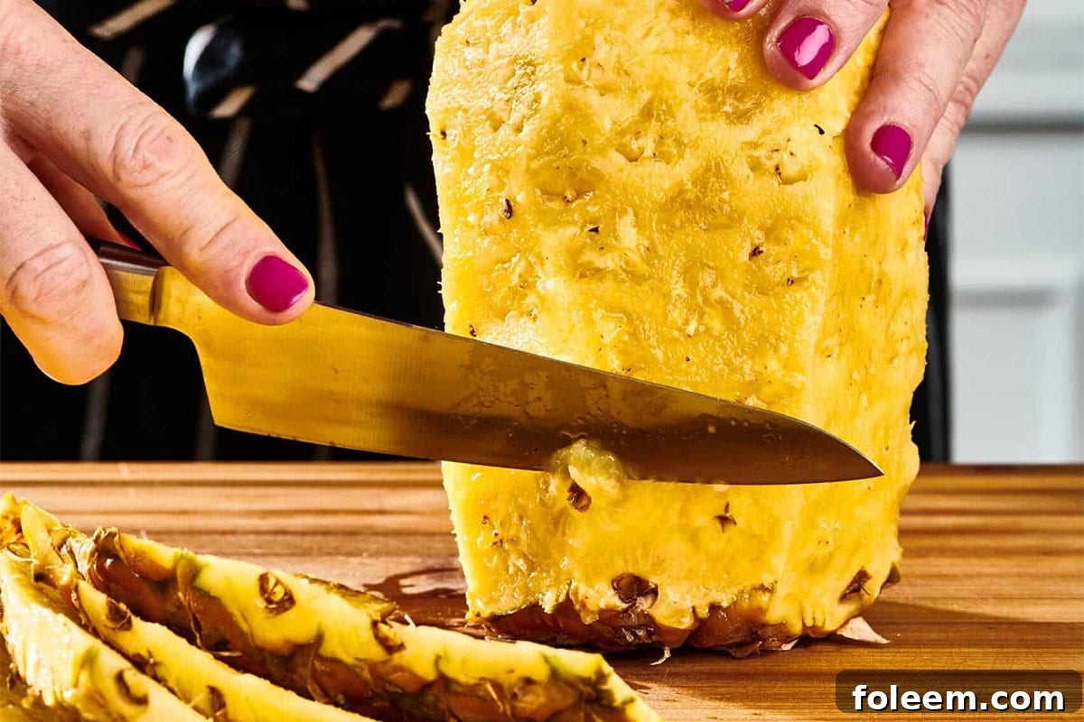 Woman using a knife to get all remaining skin off of a pineapple.