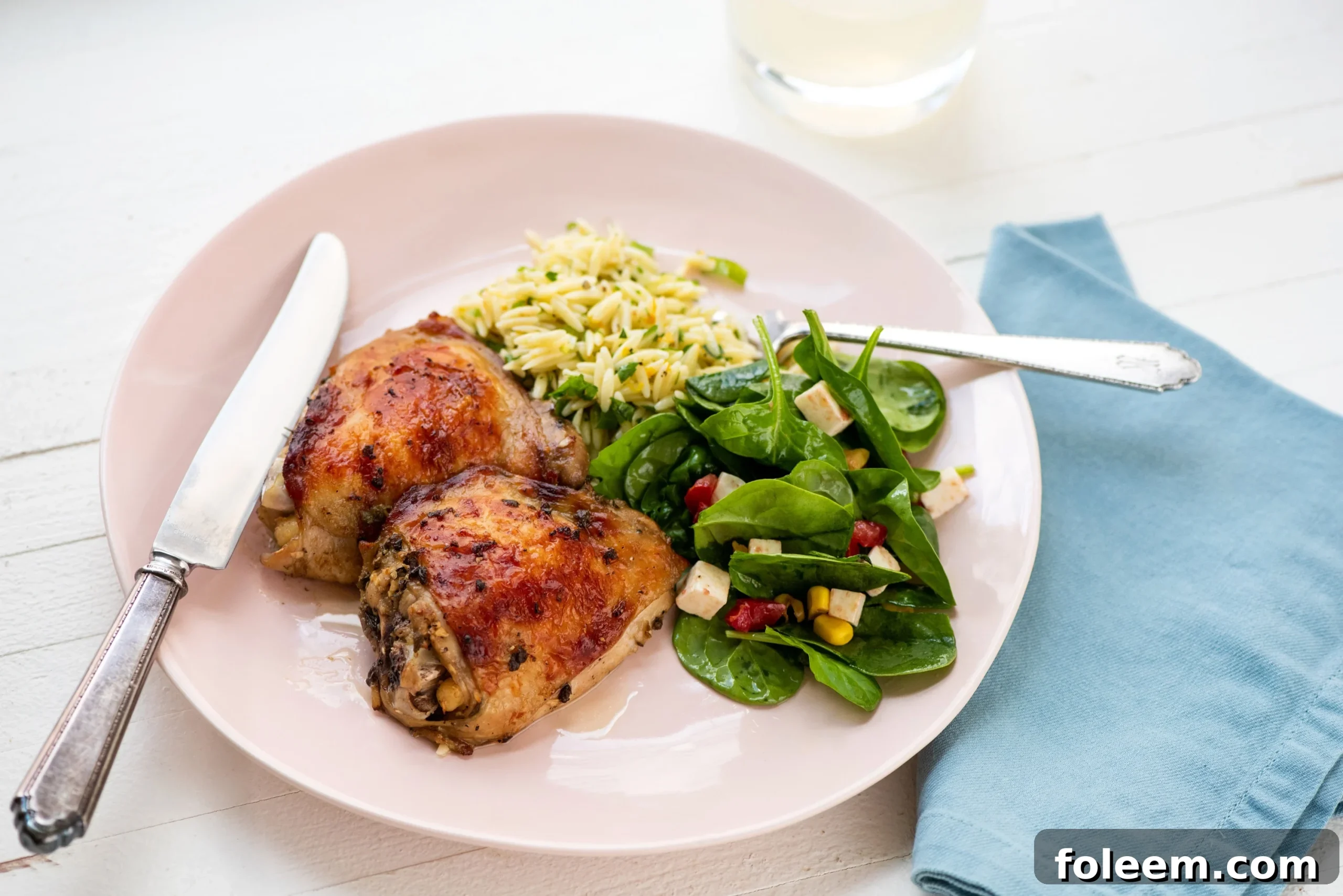 Greek Roasted Chicken Thighs  with sides on pink plate.