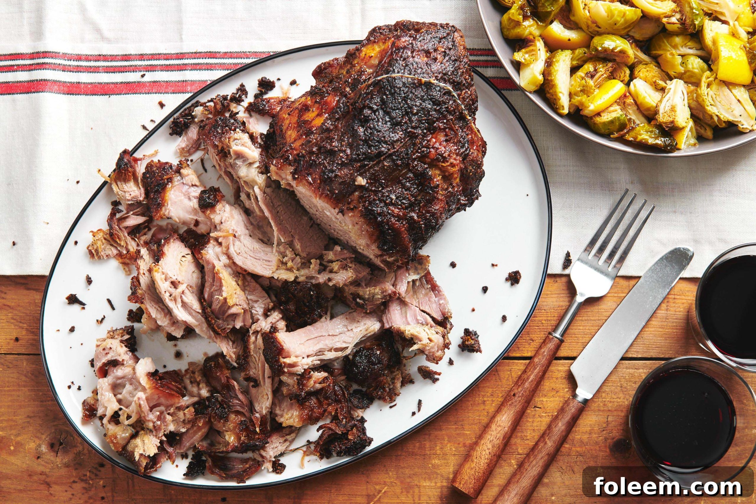 Sliced Fall-Apart Roasted Pork Shoulder with Rosemary, Mustard and Garlic on serving plate.