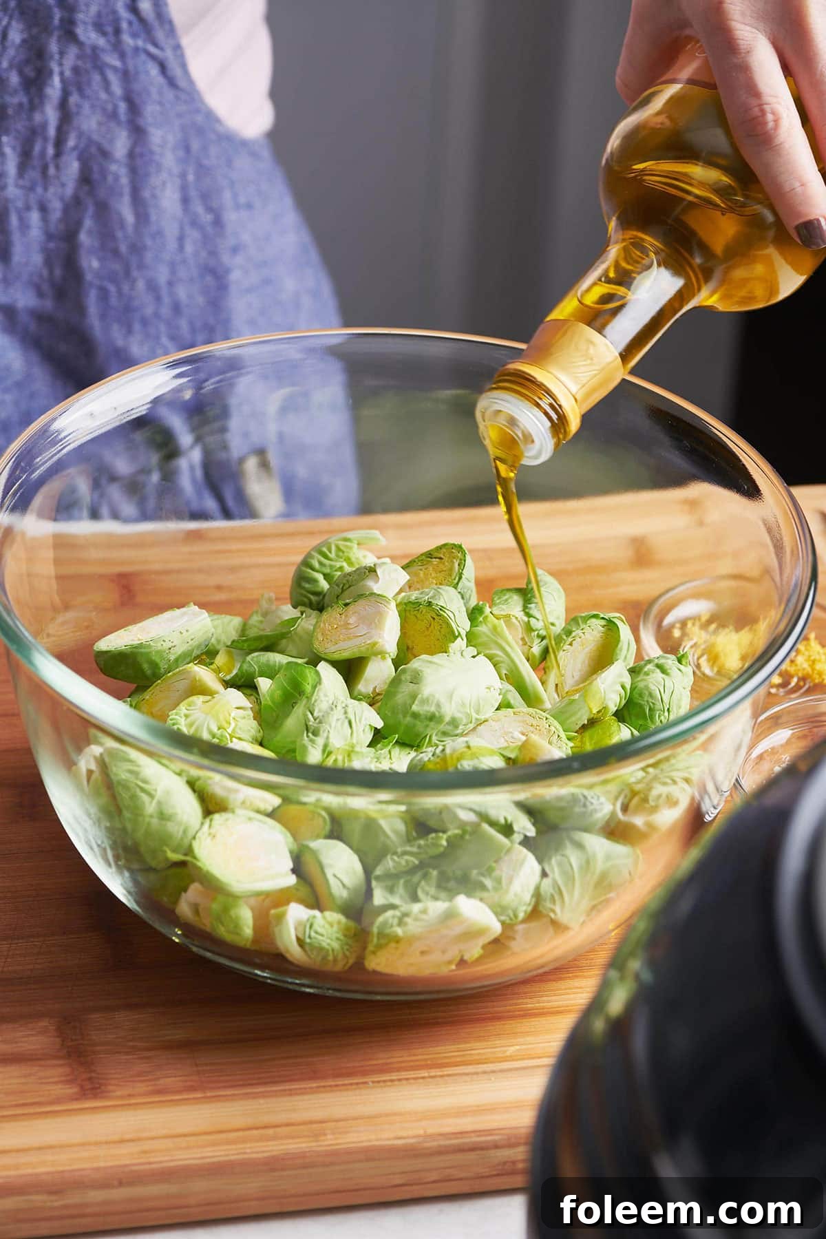 Pouring oil over Brussels sprouts.