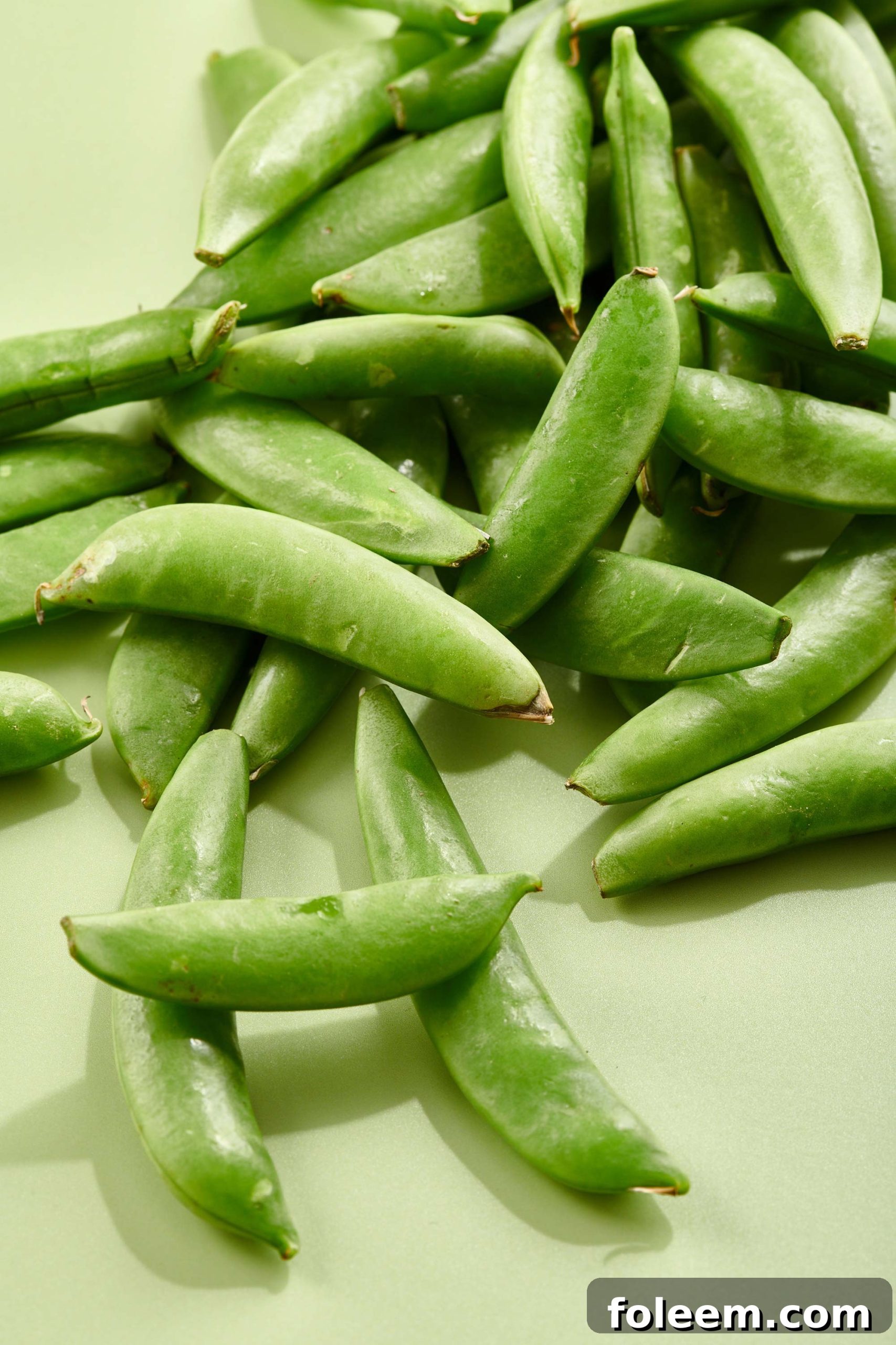 Sugar Snap Peas on a light green surface.