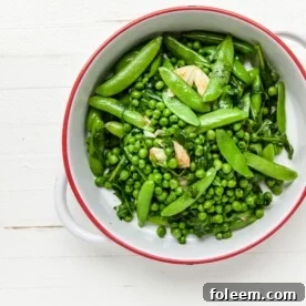 Green peas, sugar snap peas, garlic, arugula, and spinach in white bowl.