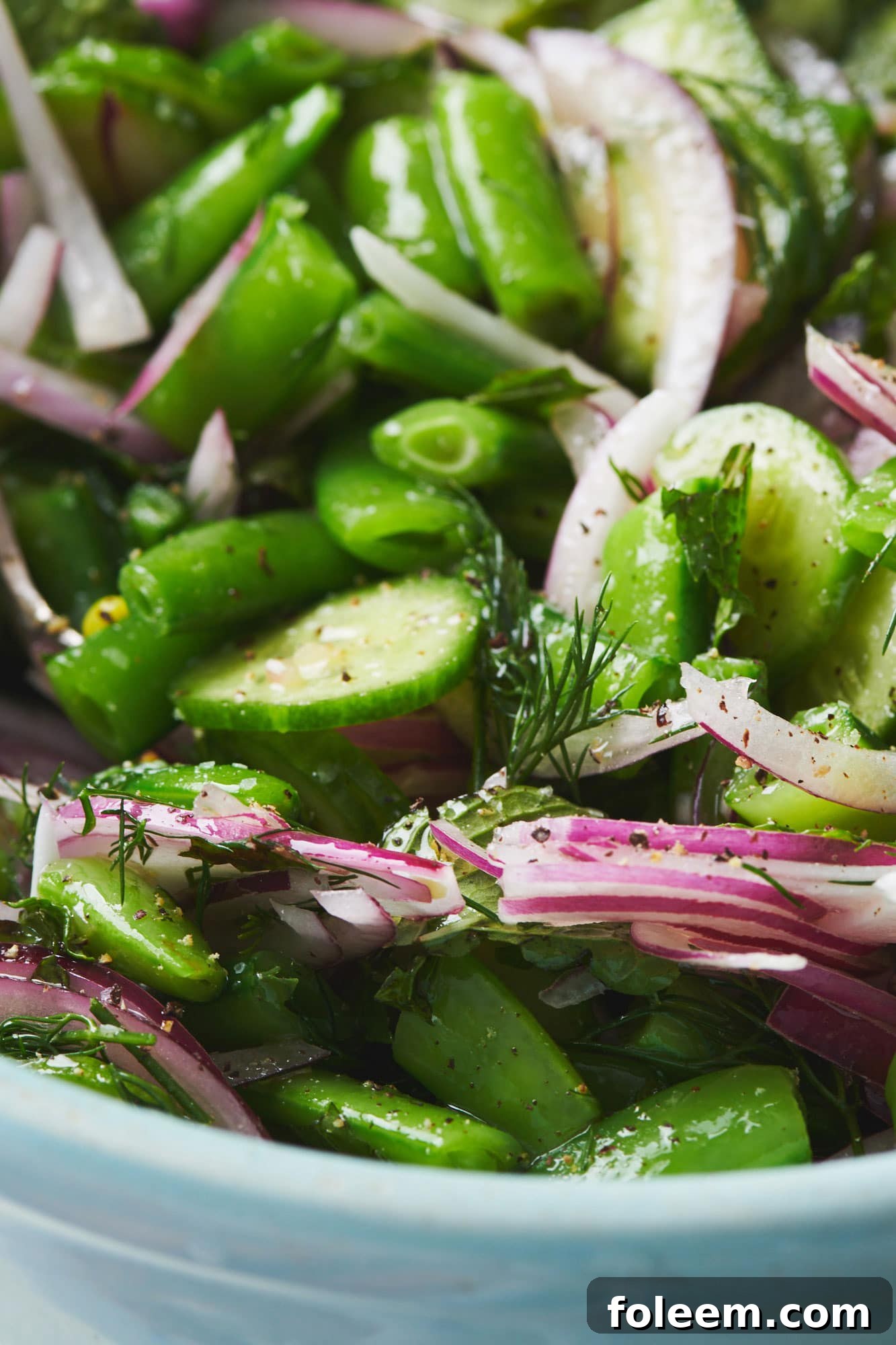 Sugar Snap Pea Salad with herbs and red onions in bowl.