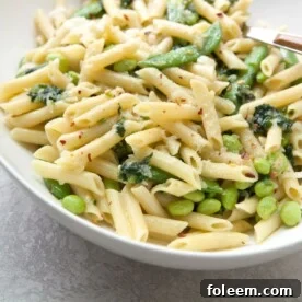 Pasta with Ramps, Edamame, and Sugar Snap Peas in a Light Parmesan Cream Sauce in white bowl.