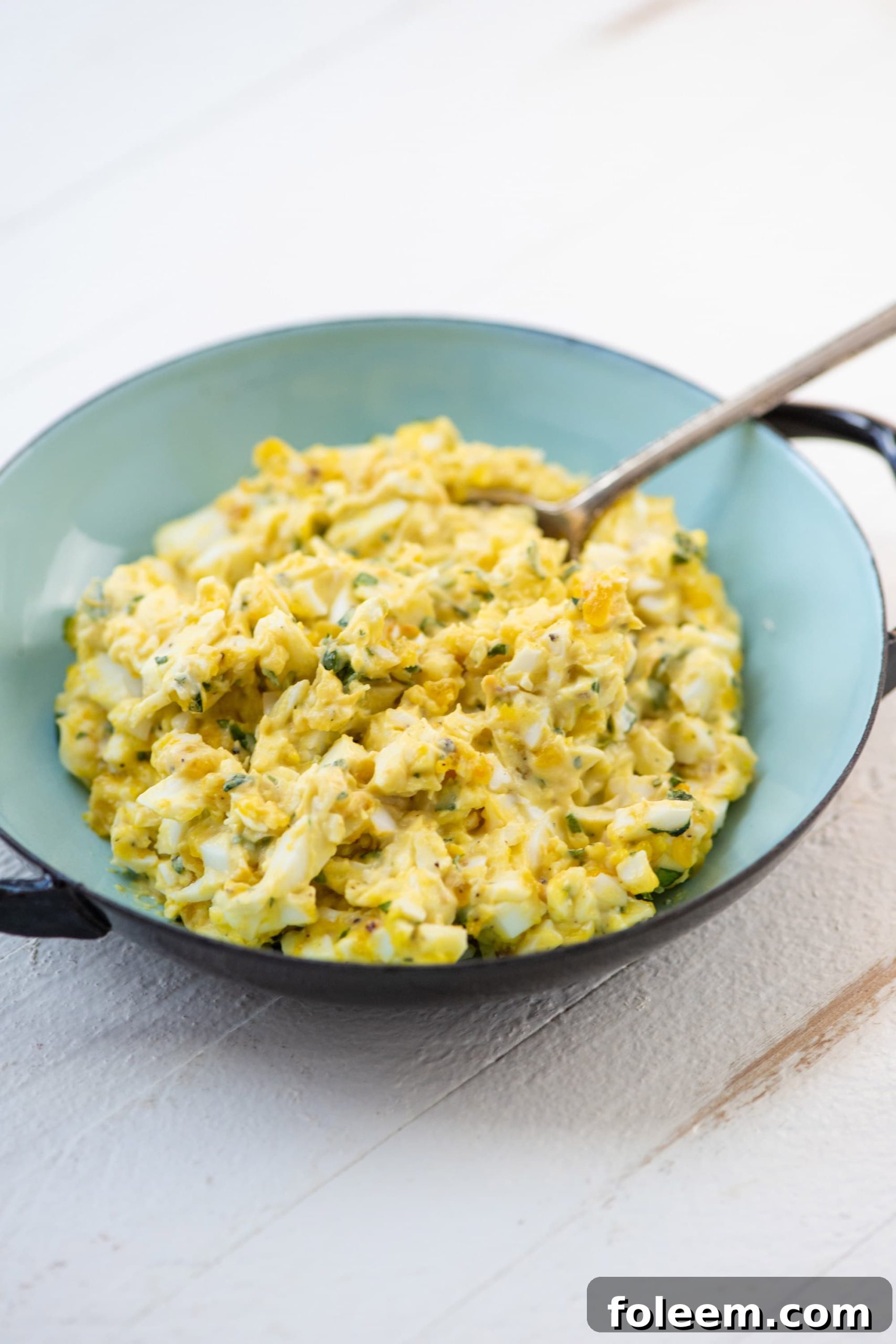 A blue bowl with orange basil egg salad.