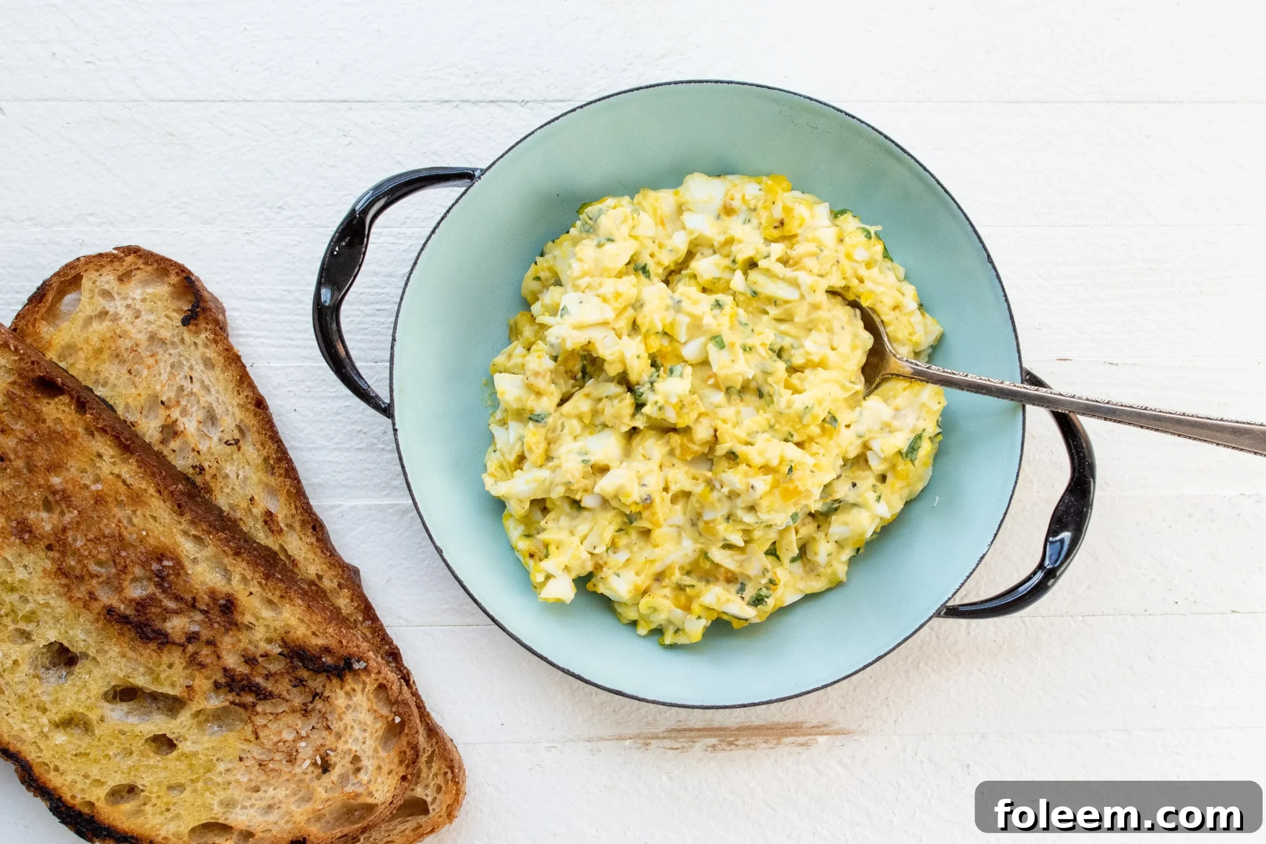 Egg Salad in a blue bowl with toast next to it.