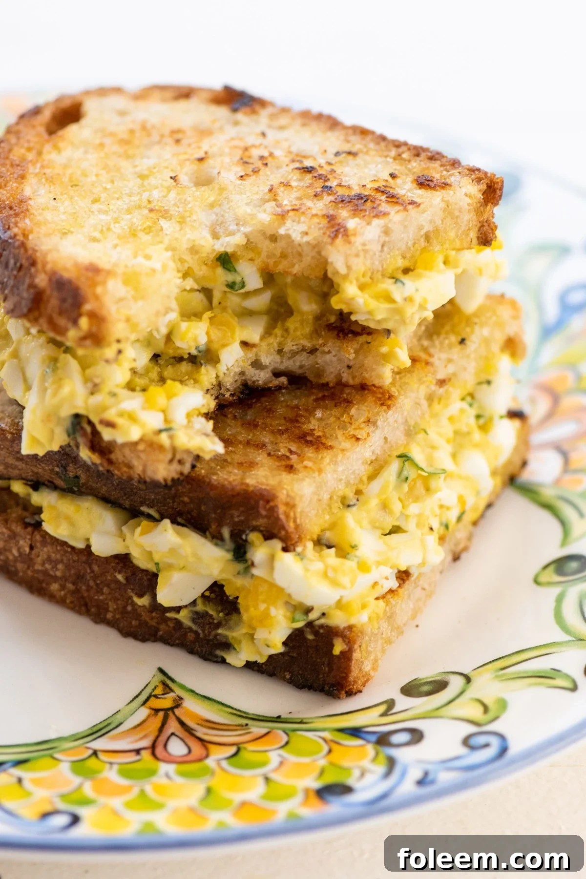 An egg salad sandwich with a bite taken out of it.