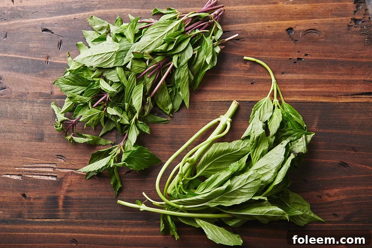 Fresh Italian and Thai basil on a wooden board.