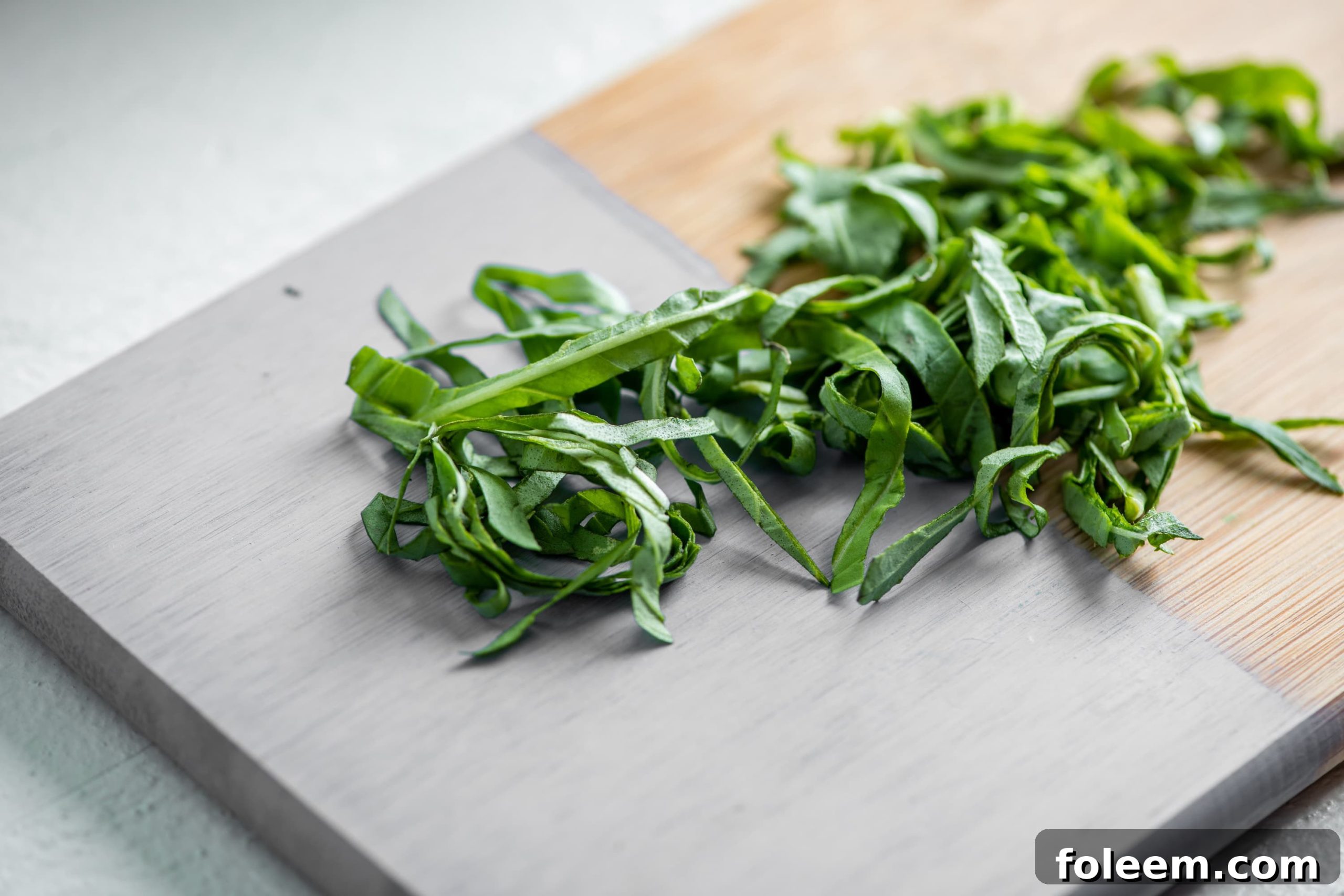 Thinly sliced or chiffonaded basil on a painted cutting baord.