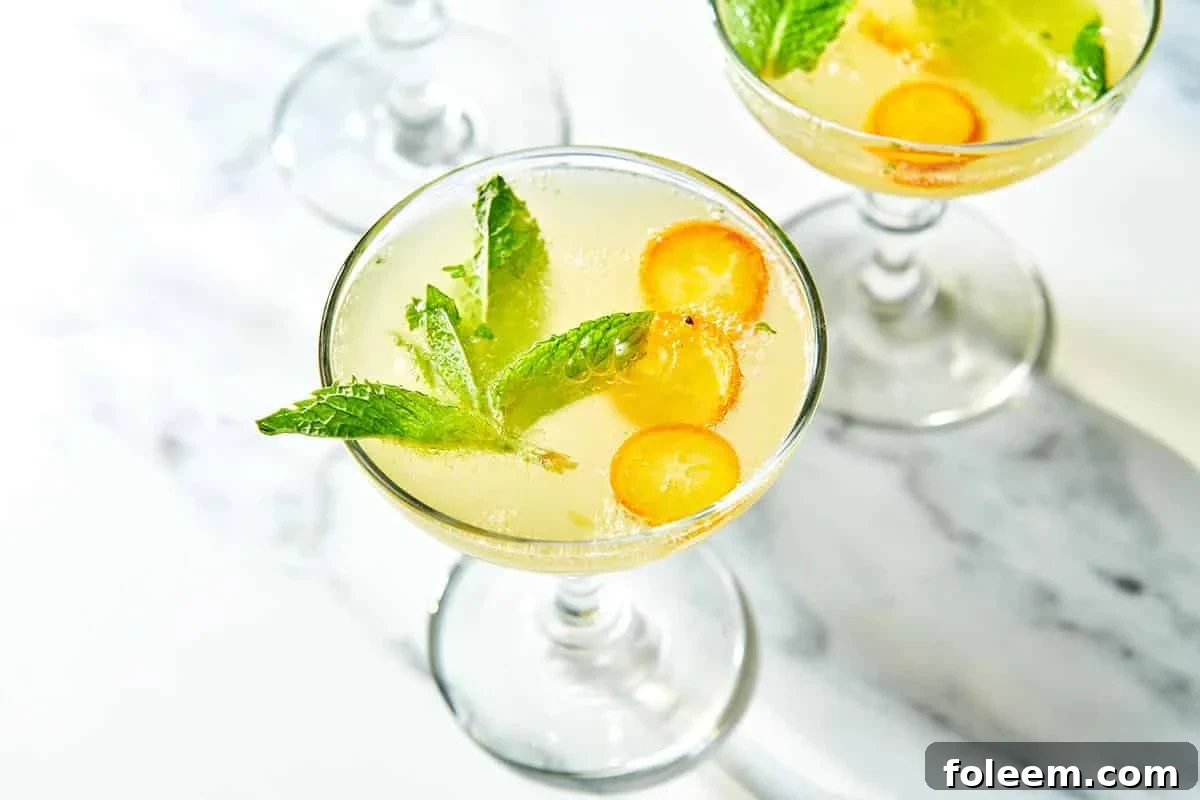 Sparkling cocktail with fresh mint and sliced kumquats in glasses.