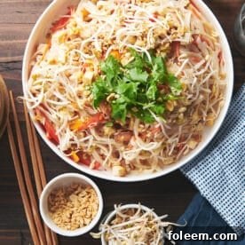 Large, white serving bowl of Pad Thai on a wooden table.