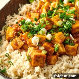Orange Tofu on a bed of rice in serving dish.