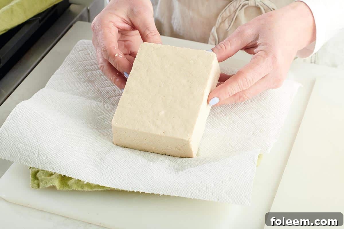 Woman placing tofu on paper towels.