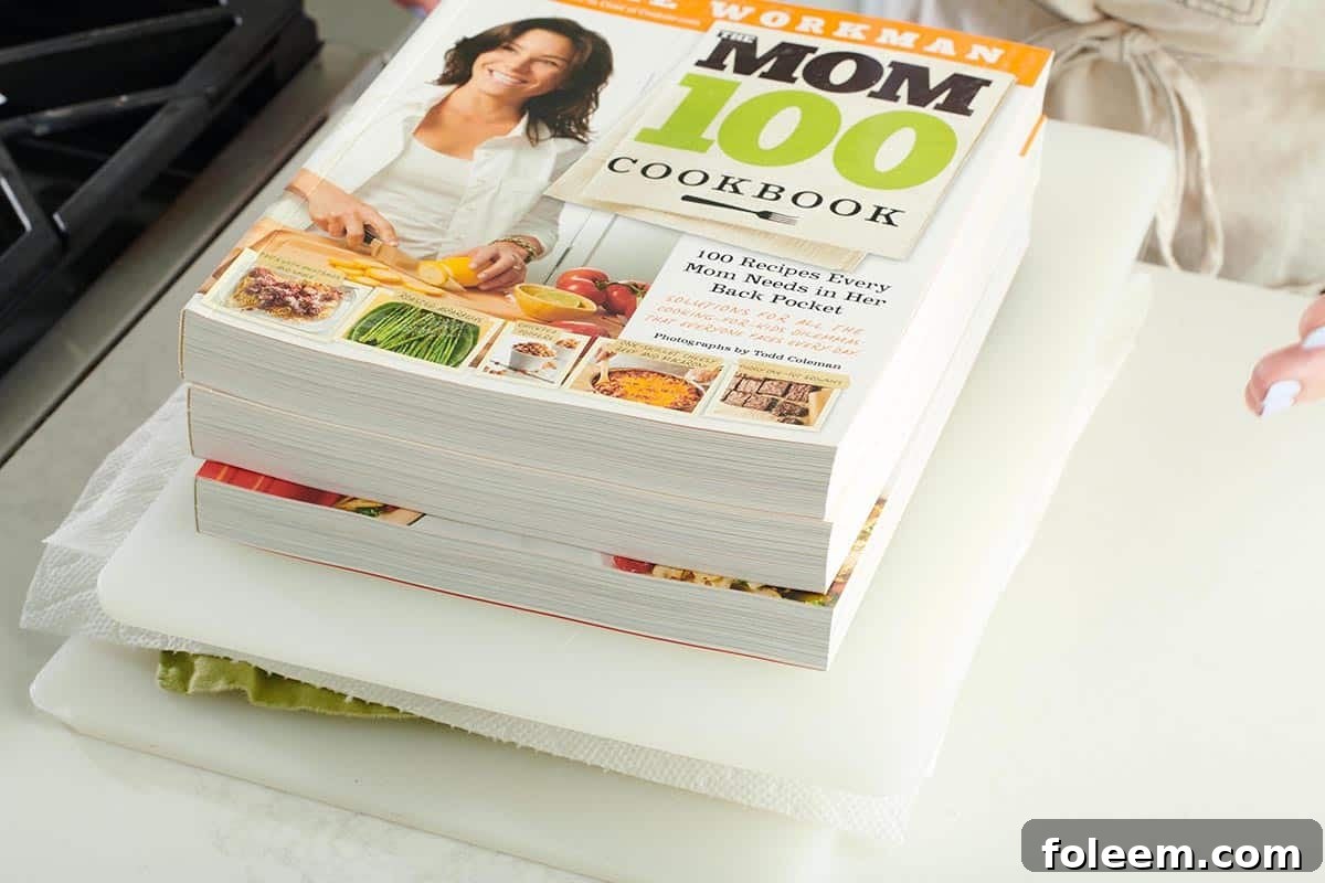 The Mom 100 Cookbook pressing tofu on counter.