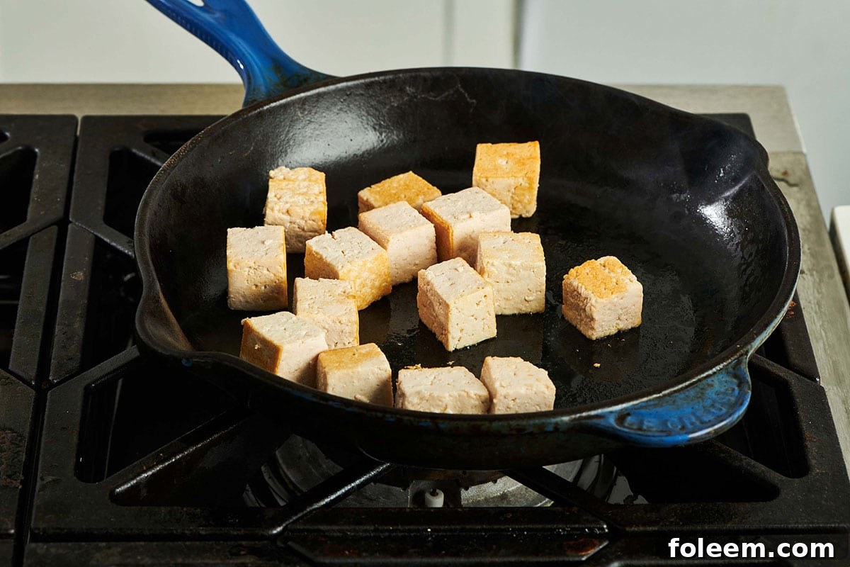 Cooking cubed tofu in pan on stove.