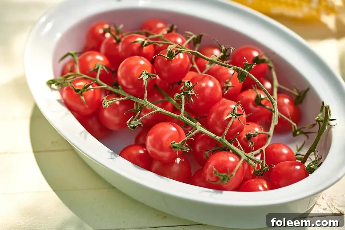 Roasted Cherry Tomatoes Recipe for Flavorful Side Dish 7 White bowl filled with fresh cherry tomatoes on the vine.