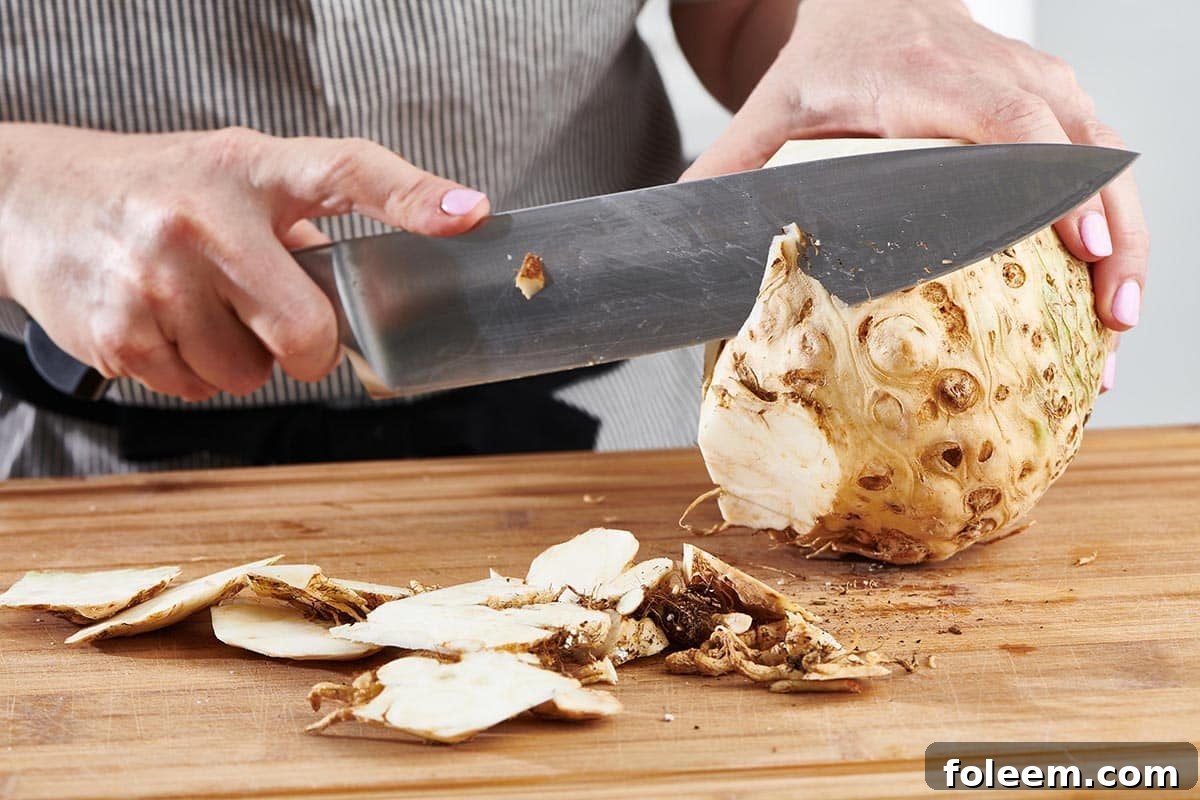 Woman using a large knife to cut the skin off of a celeriac.